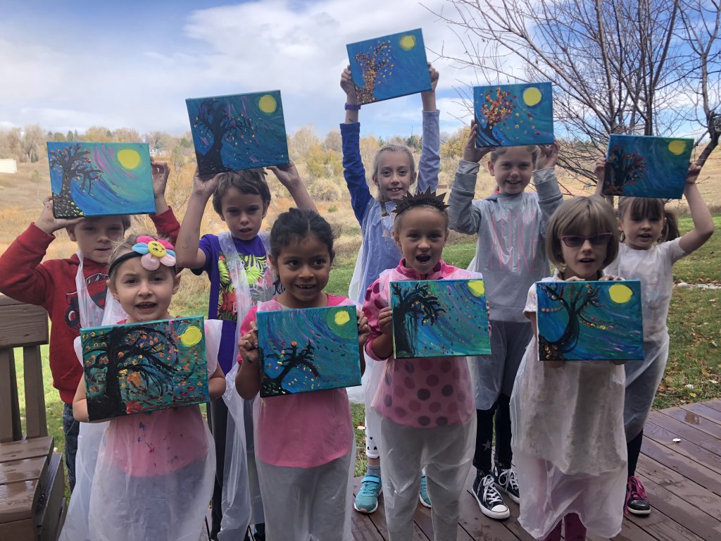 Group of kids holding up paintings